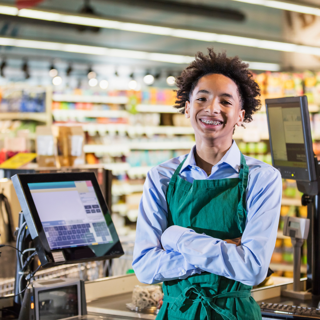 A Young Person stands behind a cash register in a retail store.