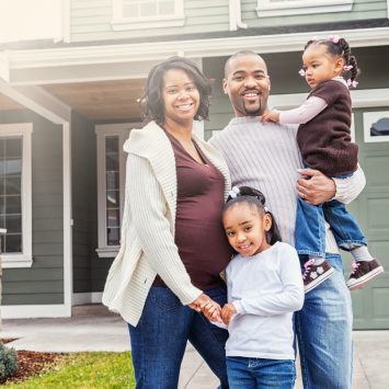 A happy African American Family stand in front of their new home.